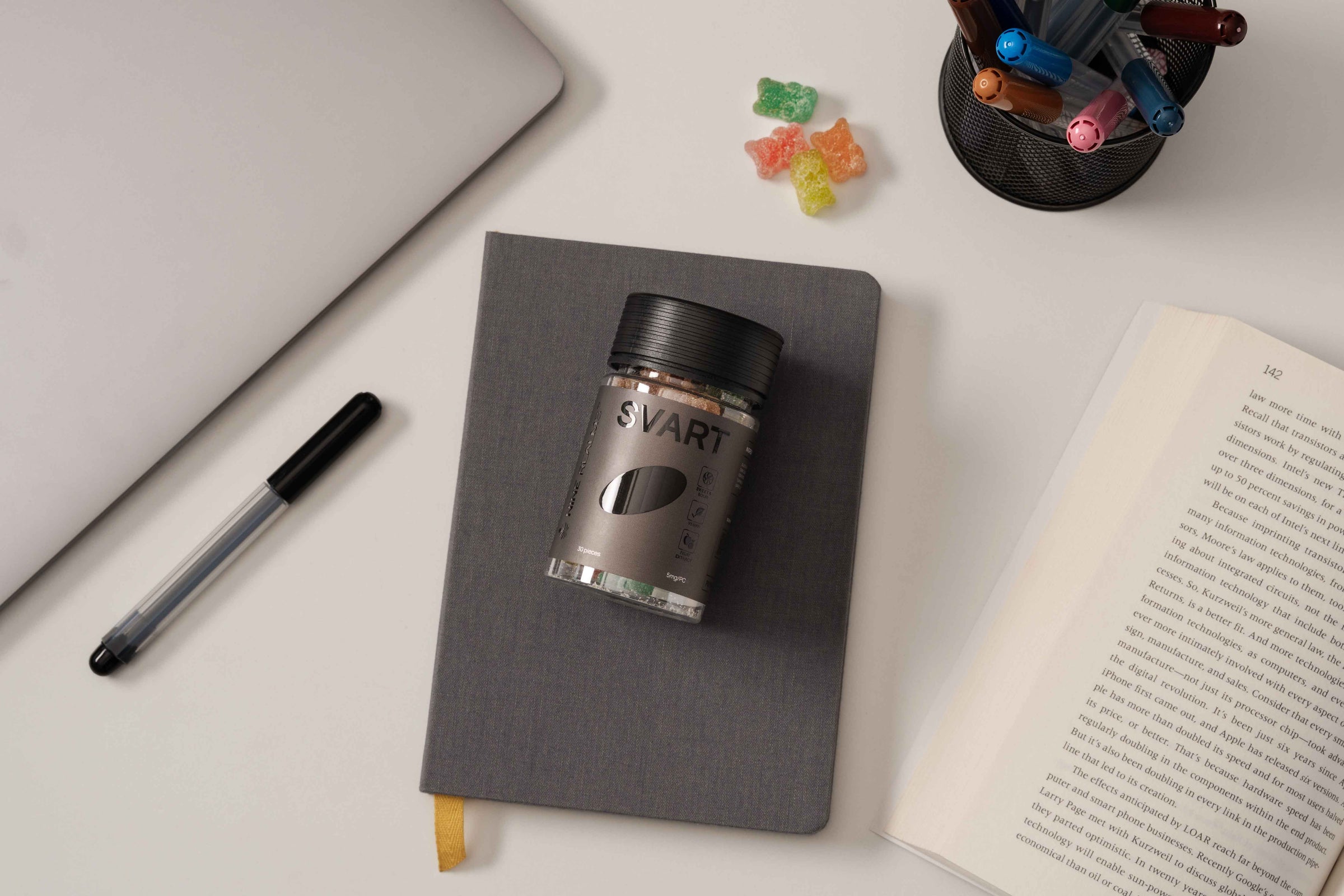 Nine Realms SVART THC Gummies on a grey journal and a macbook nearby