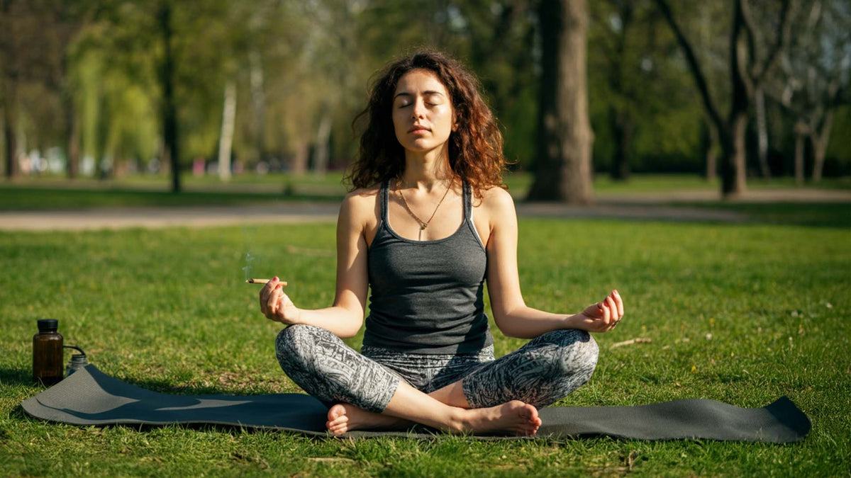 woman meditating in a park while holding a nine realms joint