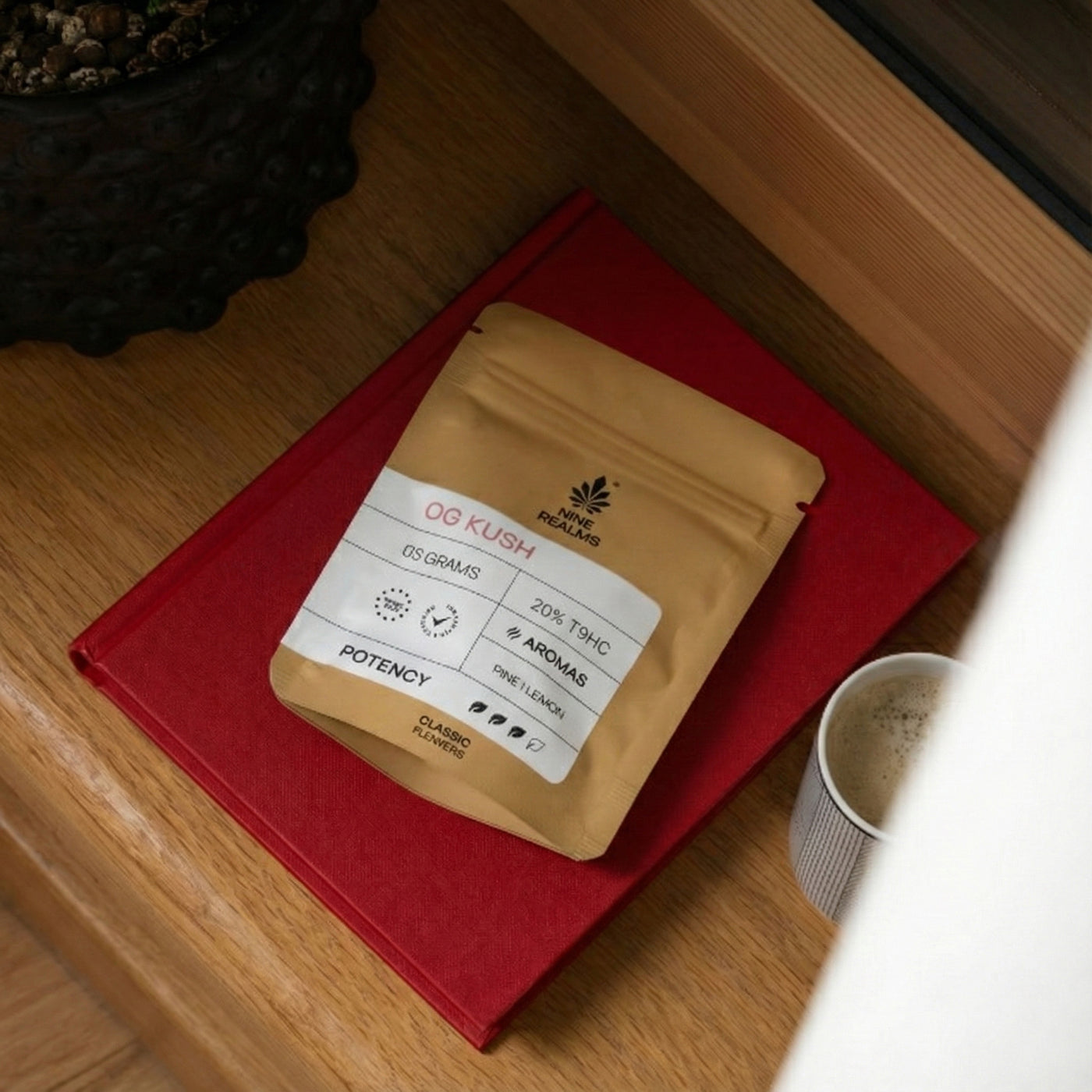 Nine Realms OG Kush Cannabis Flower T9HC on a table with coffee