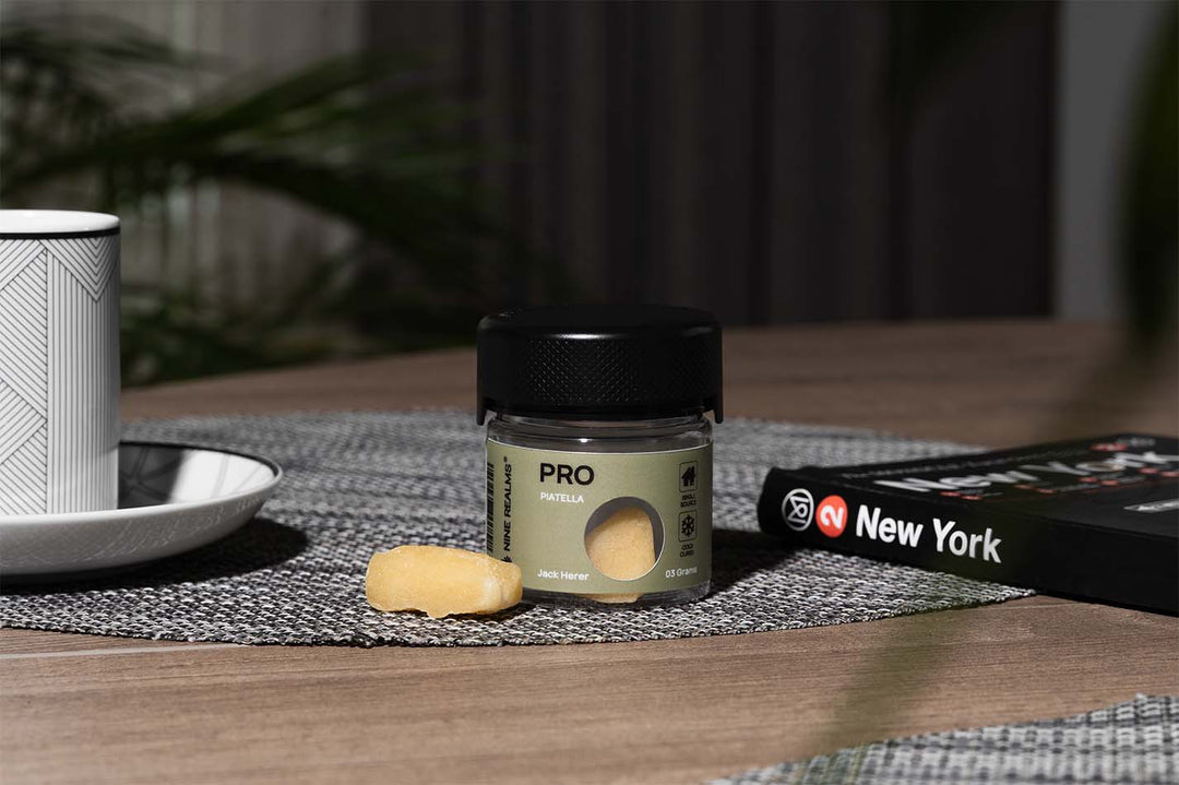 Nine Realms T9HC Piatella Hash on a wooden table with a book next to it