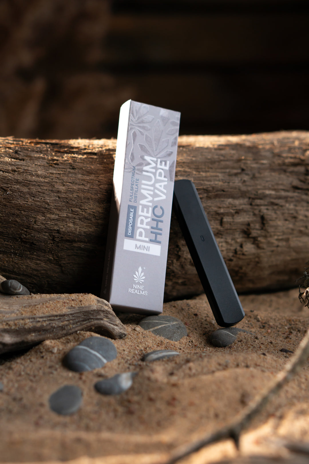 nine realms premium disposable hhc vape with packaging in a natural artistic beach composition 